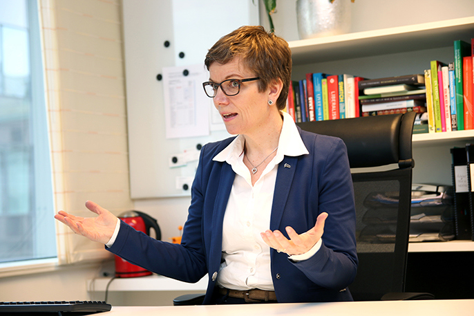 Marit Hermansen slår ut med hendene på kontoret.