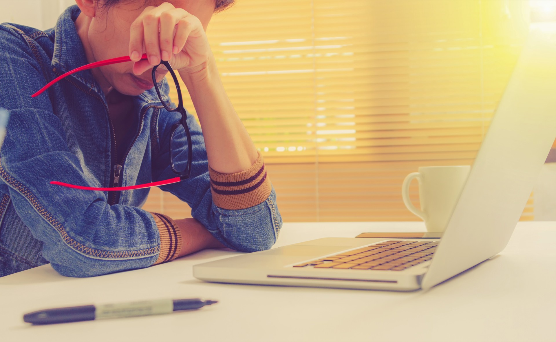 Ung person fortviler foran PC med brillene i hånda