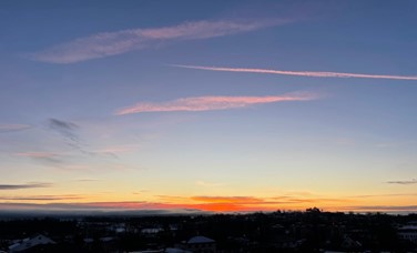 Soloppgang fra Asker rådhus januar 2025 med blå himmel, lette skyer og mørk by i nederkant av bildet
