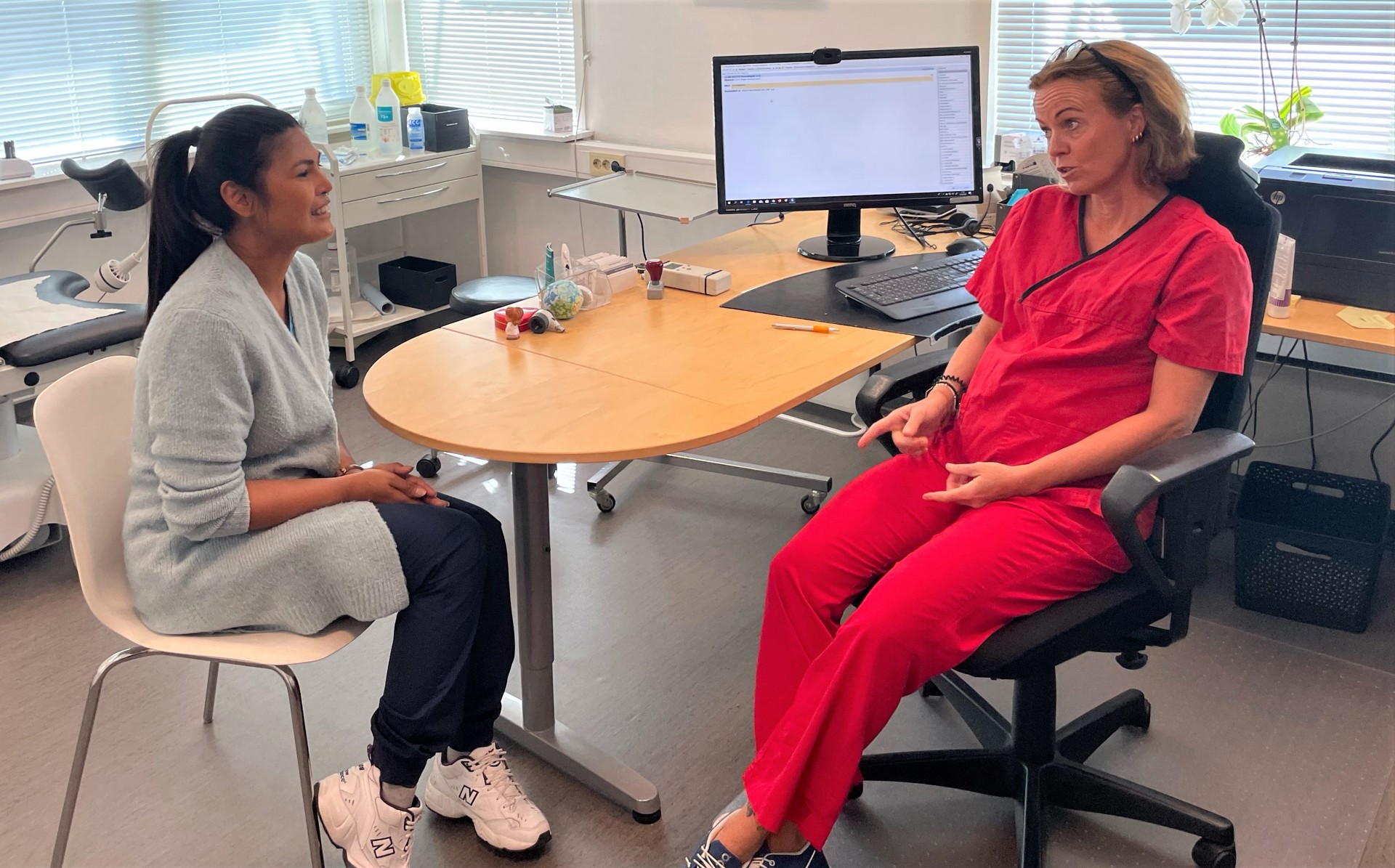 Doctors office female patient talking to female doctor
