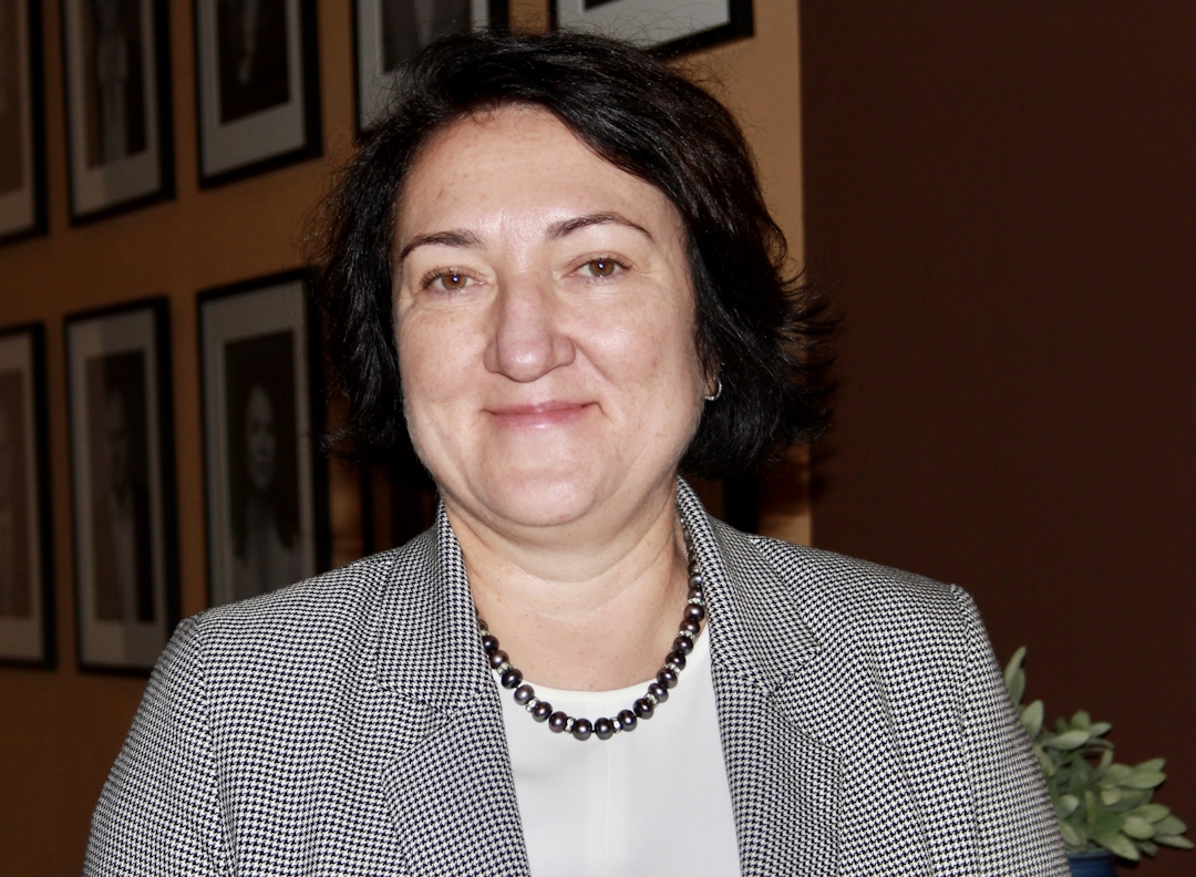 En voksen smilende kvinne med svart hår