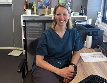 Kvinnelig lege ved pult på kontor.