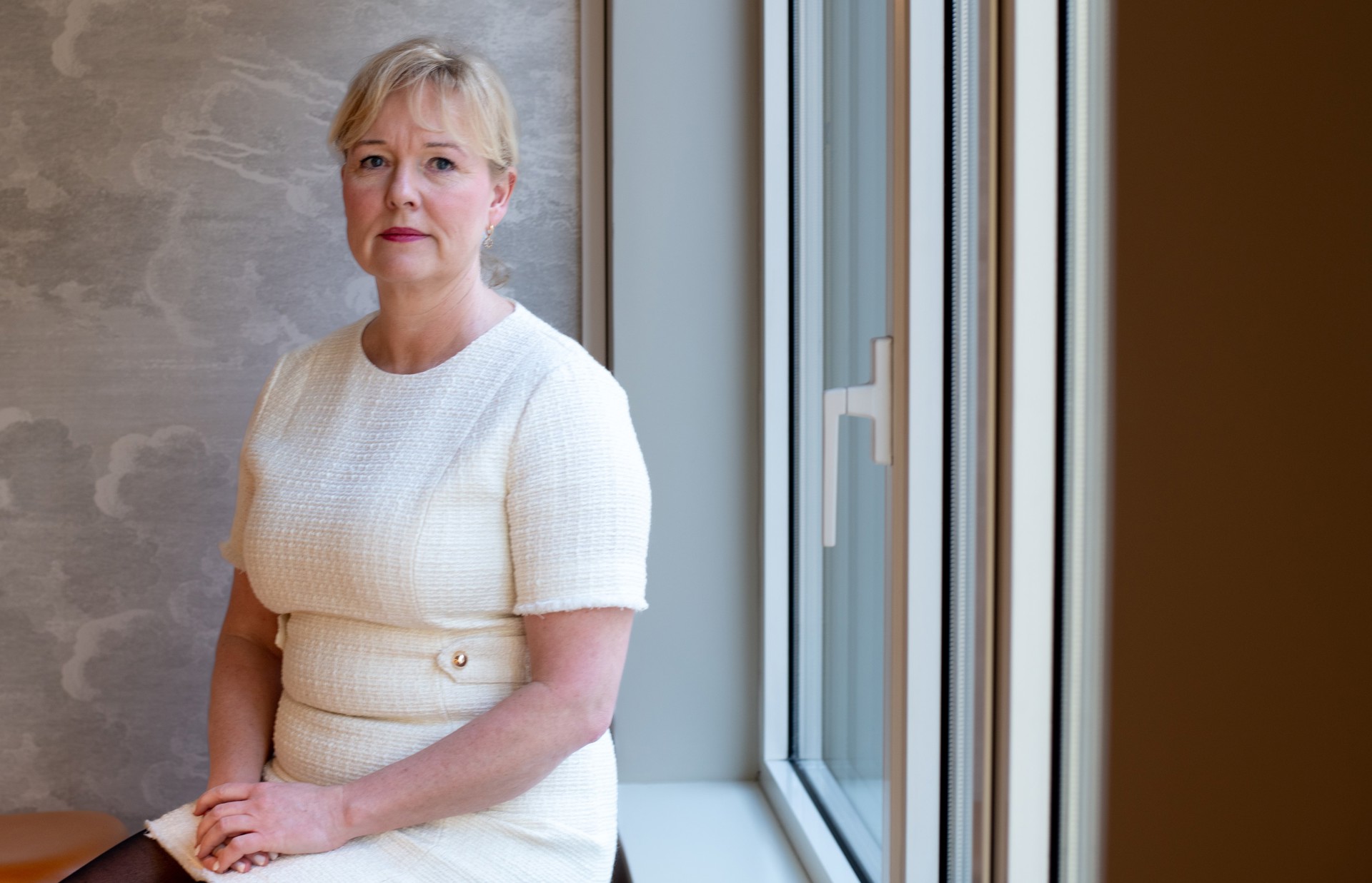 Woman in white businessdress sitting with back to window. Marte Kvittum Tangen, foto: Vidar Sandnes