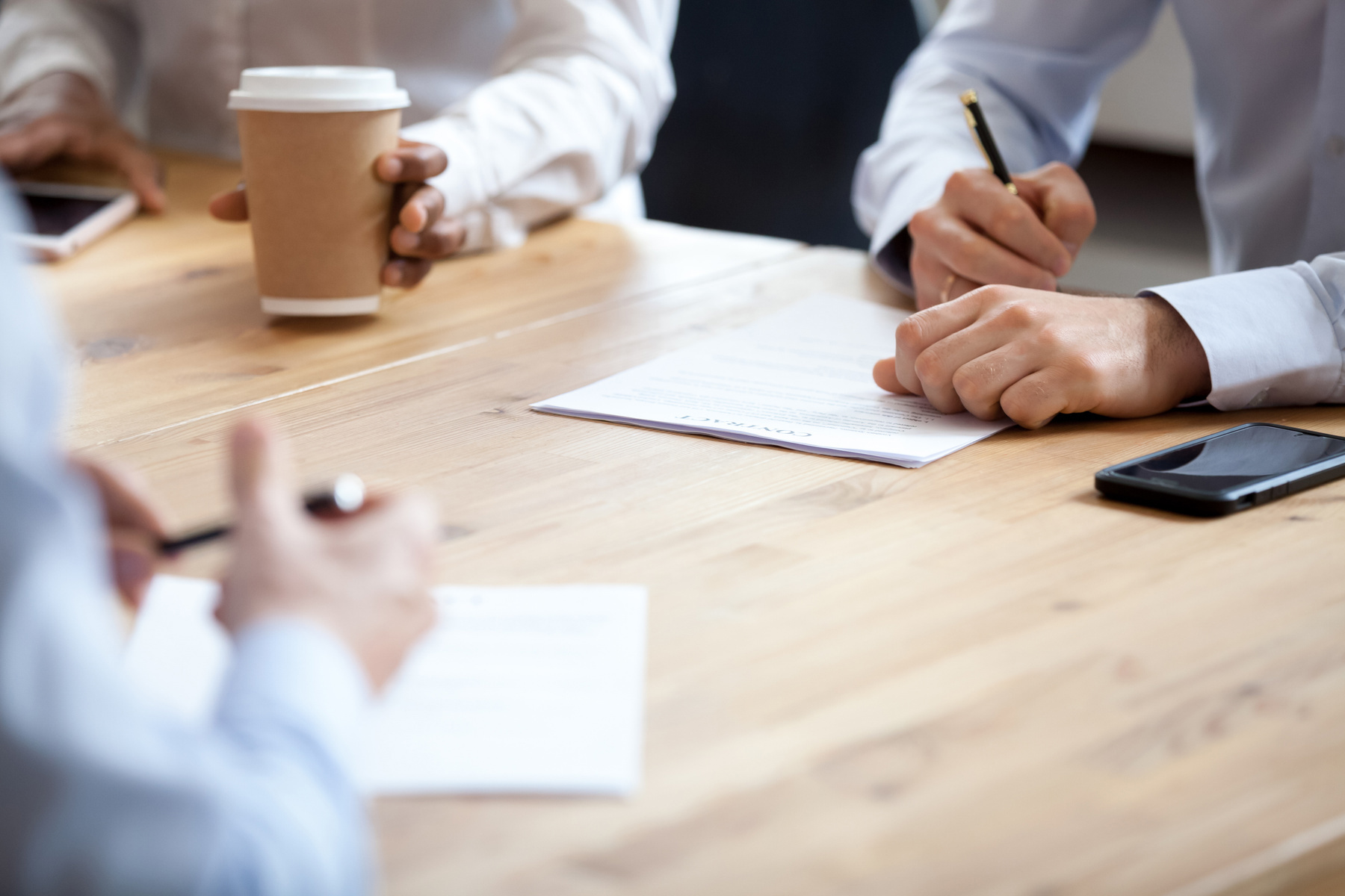 Nærbilde av 3 mennesker som gjør forhandlinger i et møte