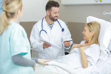 Lege som står ved en pasient som ligger i en sykeseng. Foto: Colourbox.com