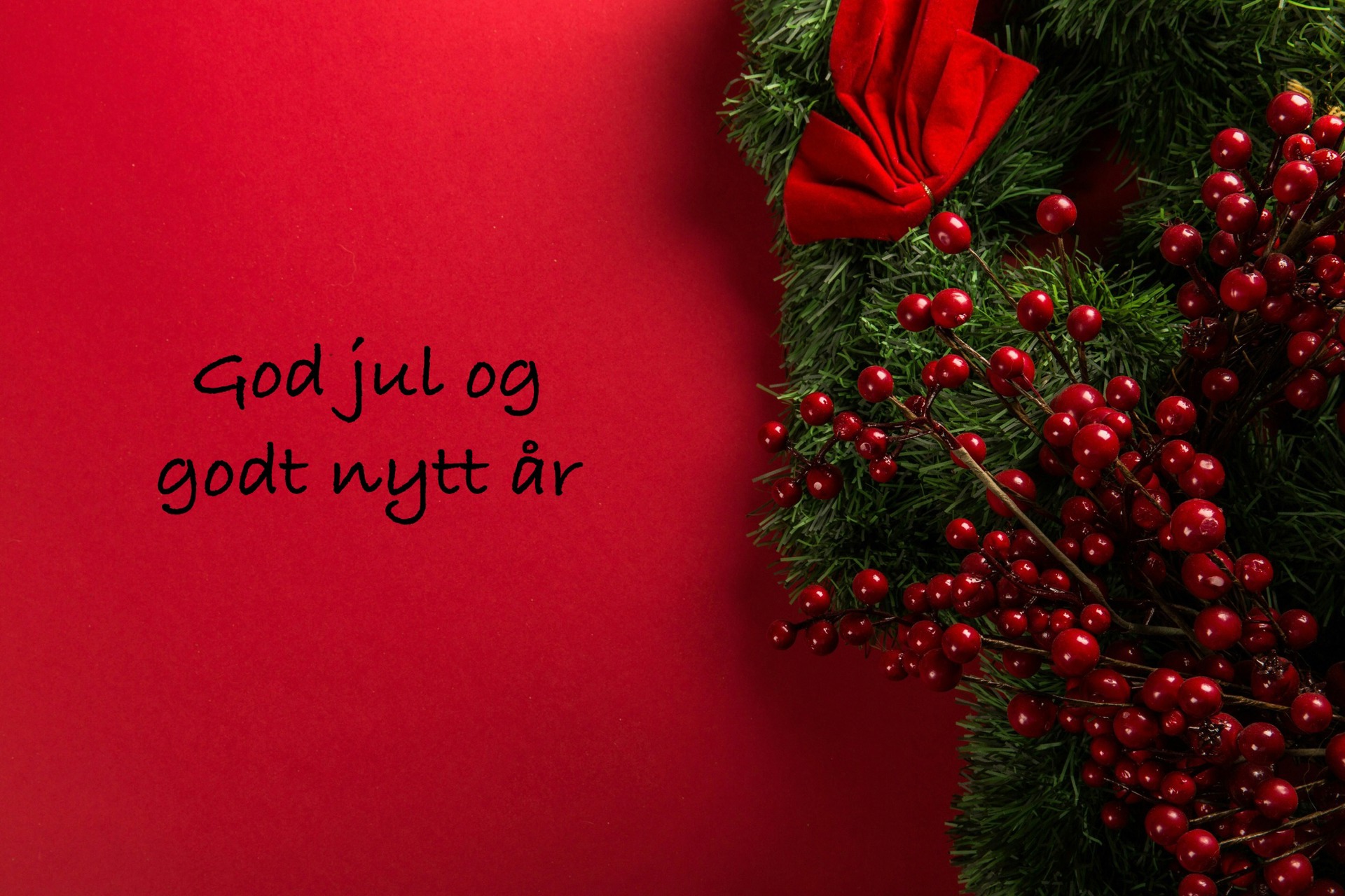 Julekrans med granbar, sløyfe og røde bær på rød bakgrunn.