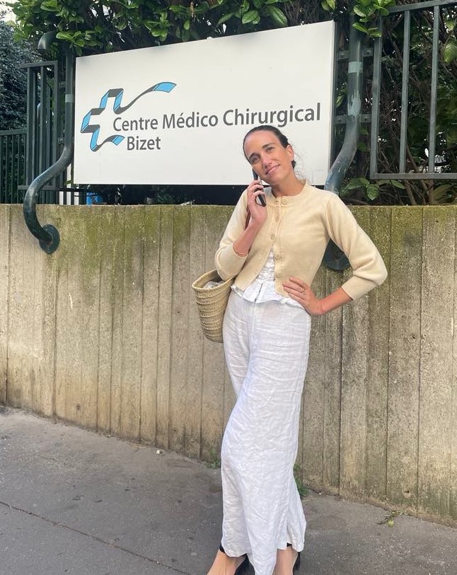 Bilde av en kvinne som står foran skiltet til sykehuset. Foto: Mie Cappelen Skovholt