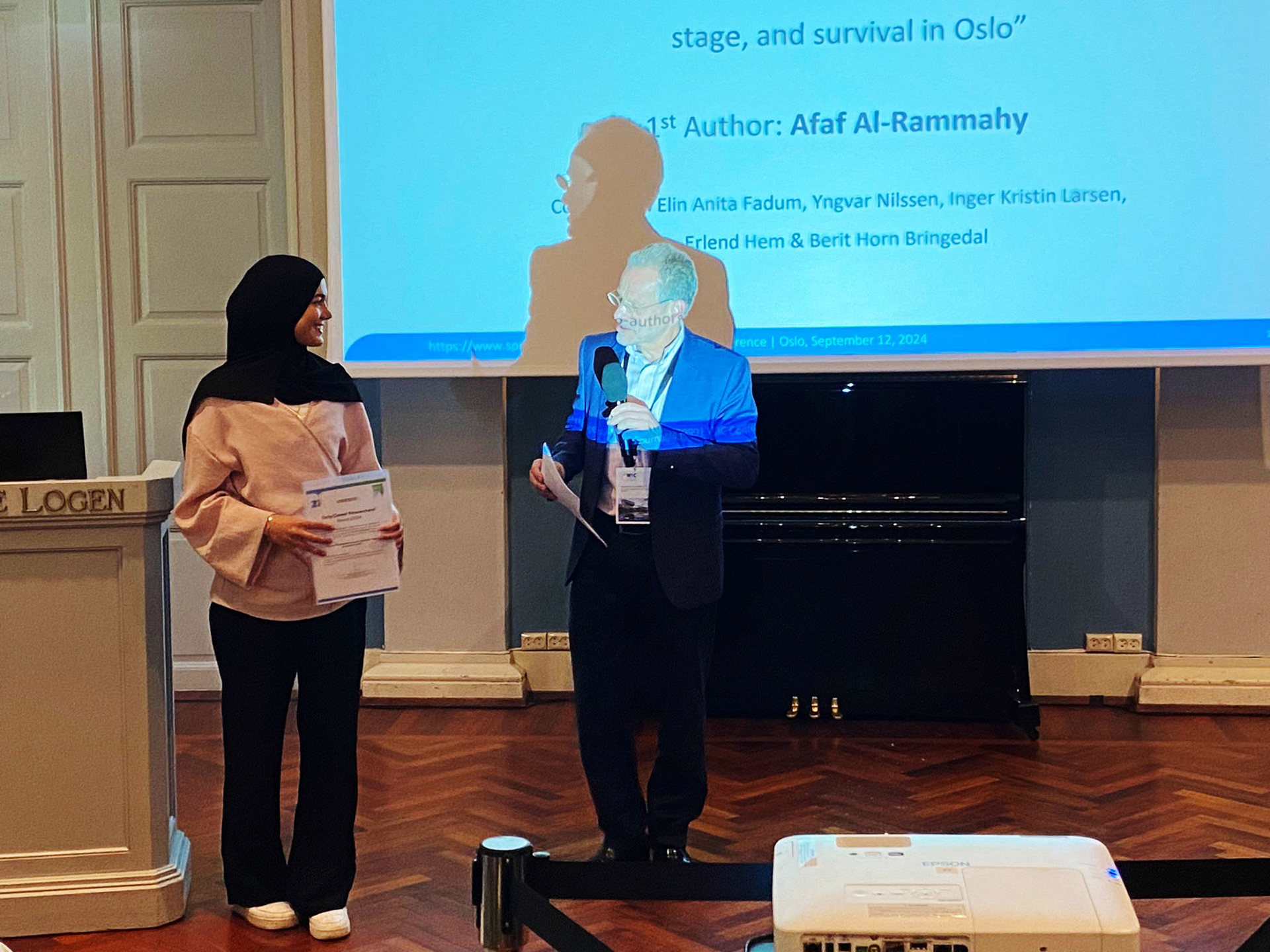Afaf Al-Rammahy til venstre i bildet med diplom. Mannlig representant for tidsskriftet til høyre.