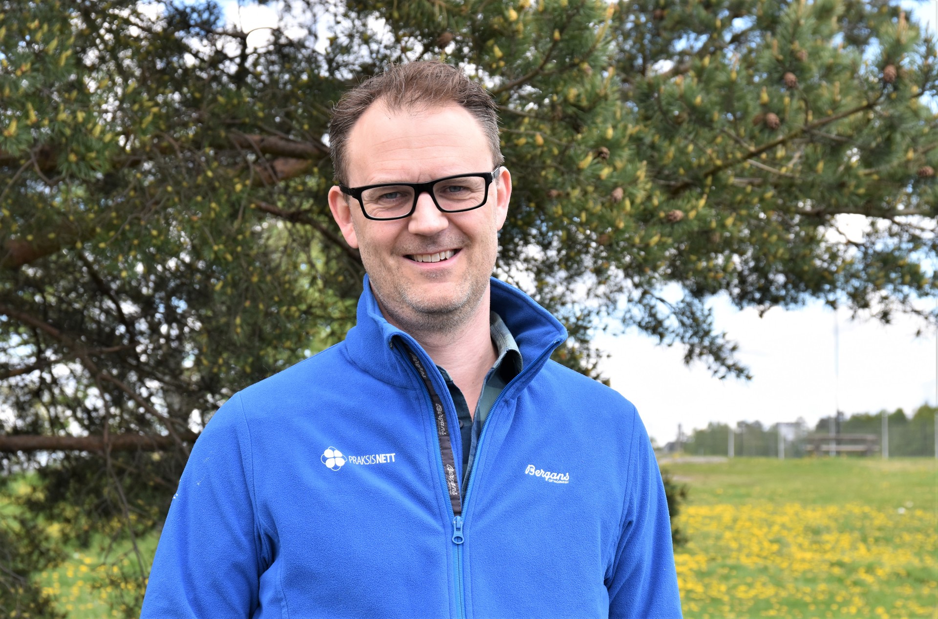 Mann i blå genser foran tre og gresseng. Espen Saxhaug Kristoffersen, overordnet leder for de regionale nettverkene i PraksisNett. Arkivfoto: Lisbeth Nilsen