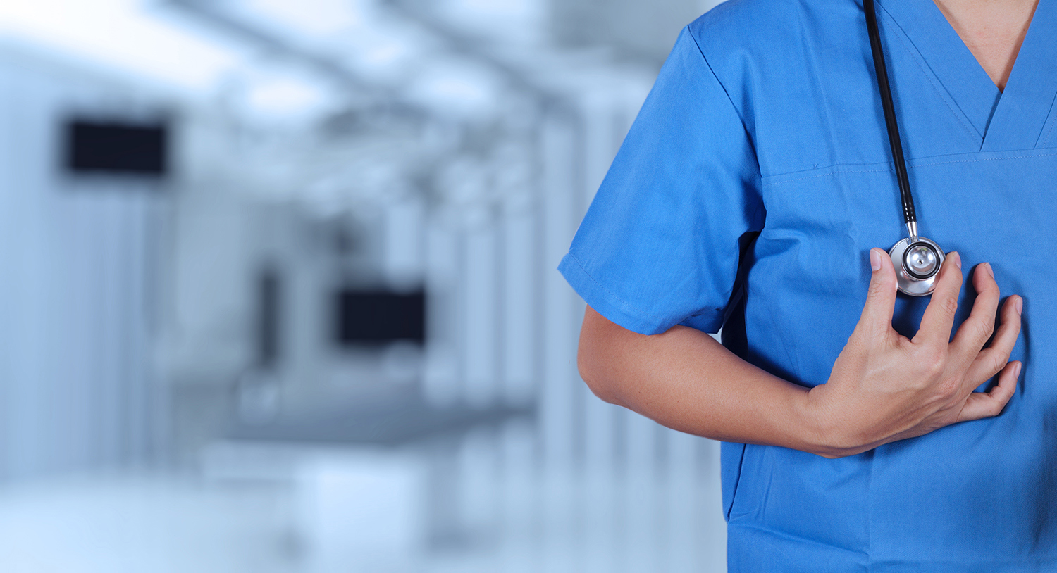 Overkropp til lege med blå sykehusskjorte, stetoskop rundt halsen. Foto: Colourbox.