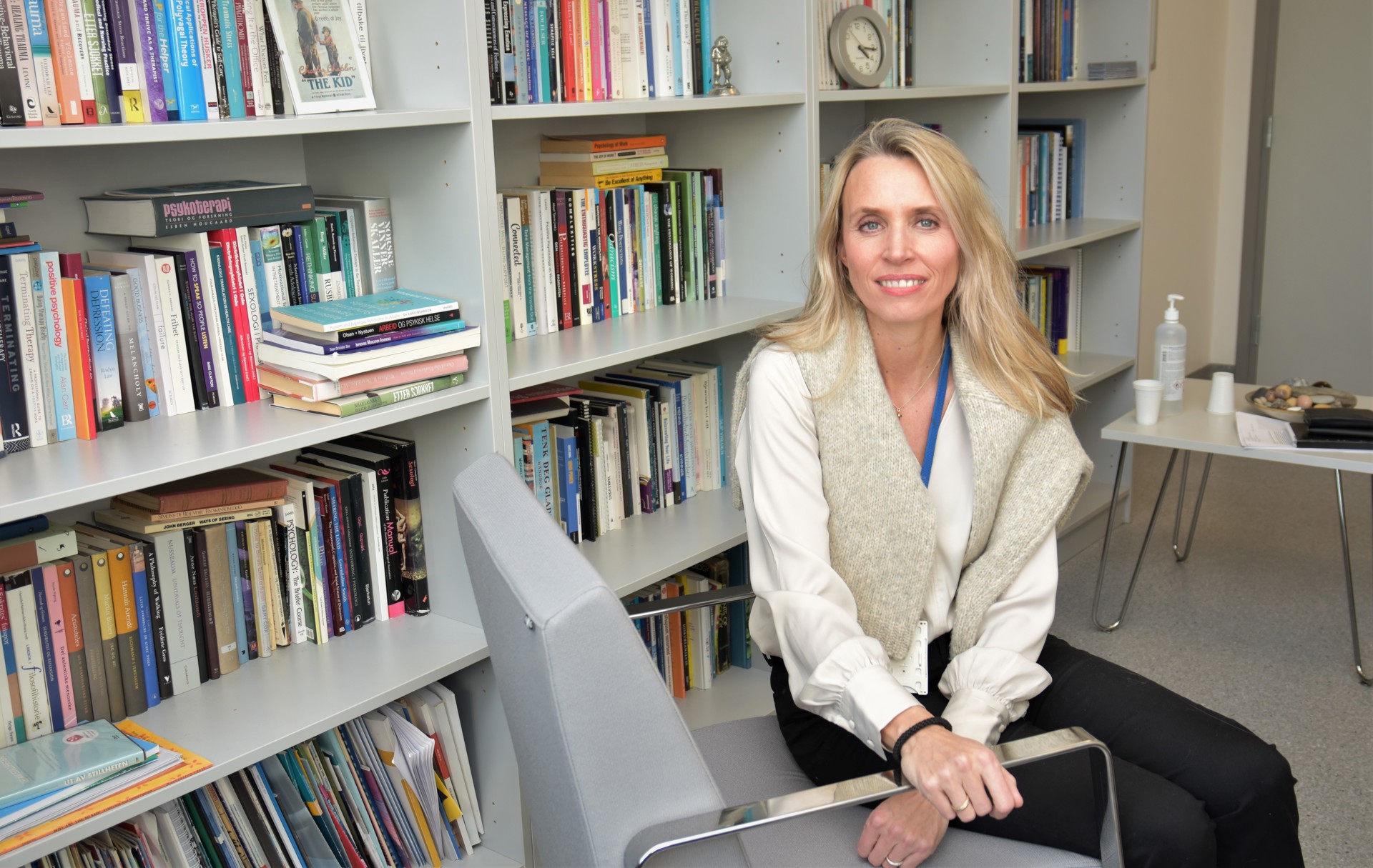 Dame i stol foran bokhylle. Ragne Gjengedal, foto Lisbeth Nilsen