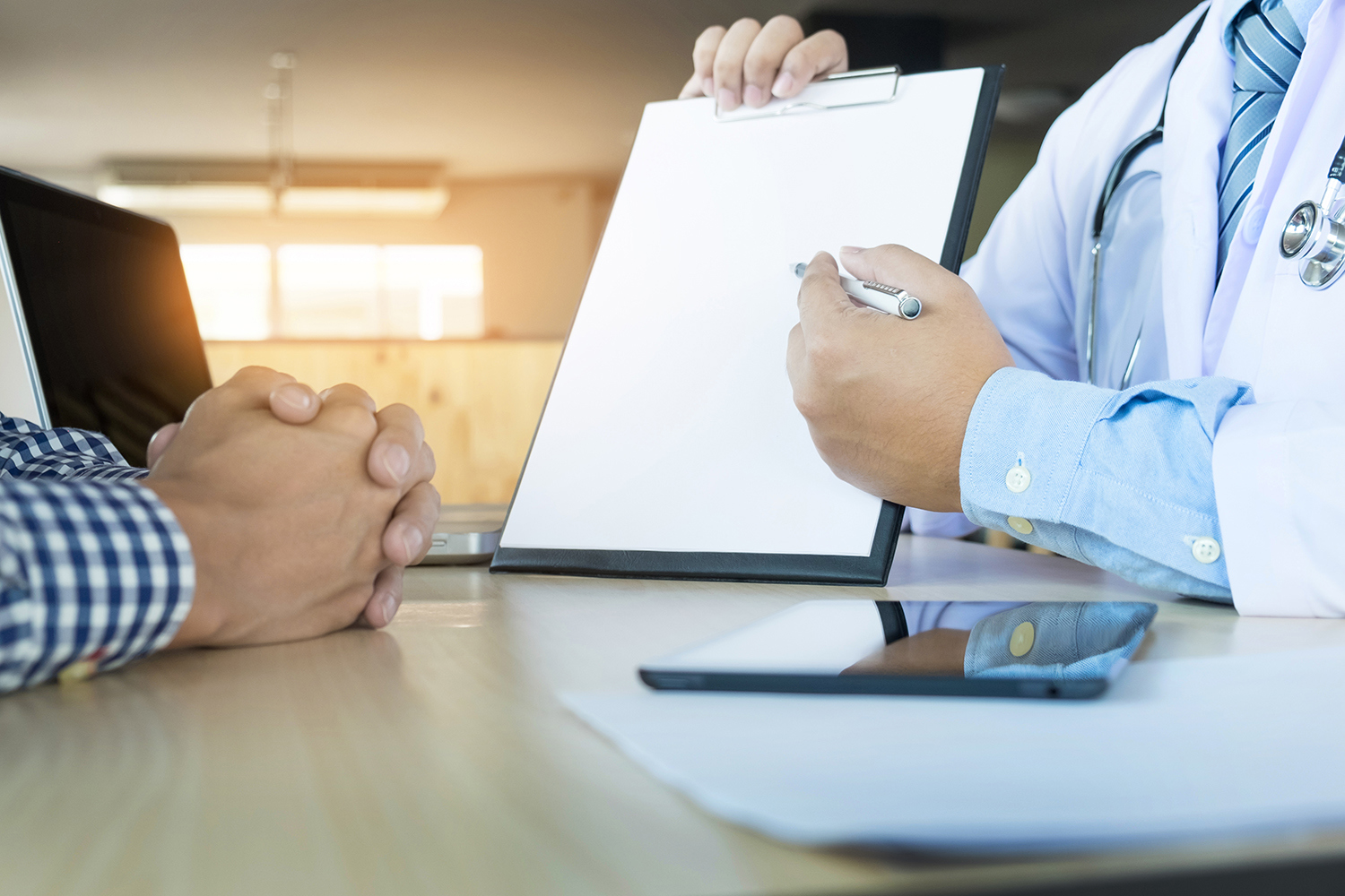 Lege peker på clipboard med en penn og viser det til pasient