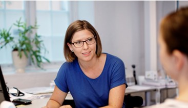 Dame på kontor med blå Tskjorte og briller