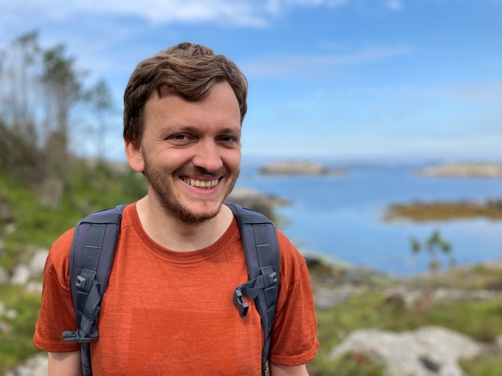 Mann med ryggsekk og havet bak. Foto: Solveig Hogstad Tveit