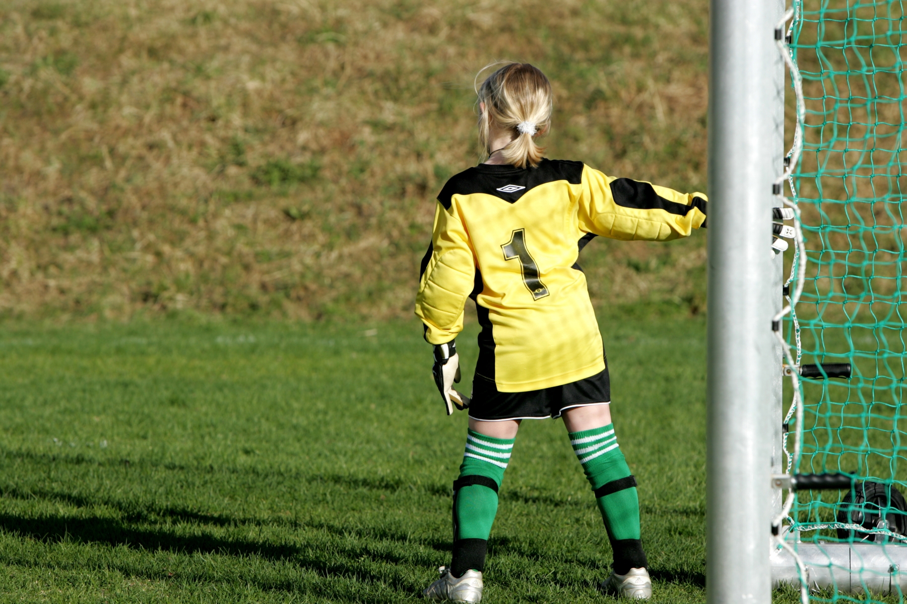 Jente i fotballdrakt som lener seg på et fotballmål. Foto: Mostphotos.com