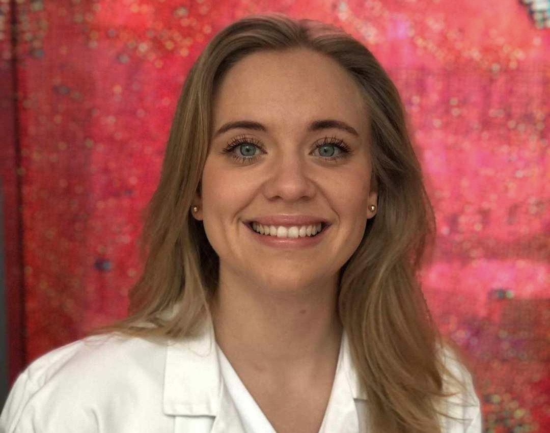 Bilde av en ung kvinne med langt hår mot rød bakgrunn.