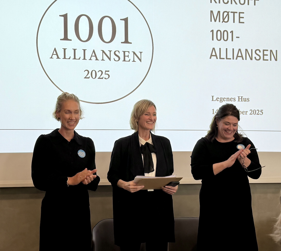 Tre kvinner i mørke klær foran en hvit skjerm med teksten 1001-alliansen 2025