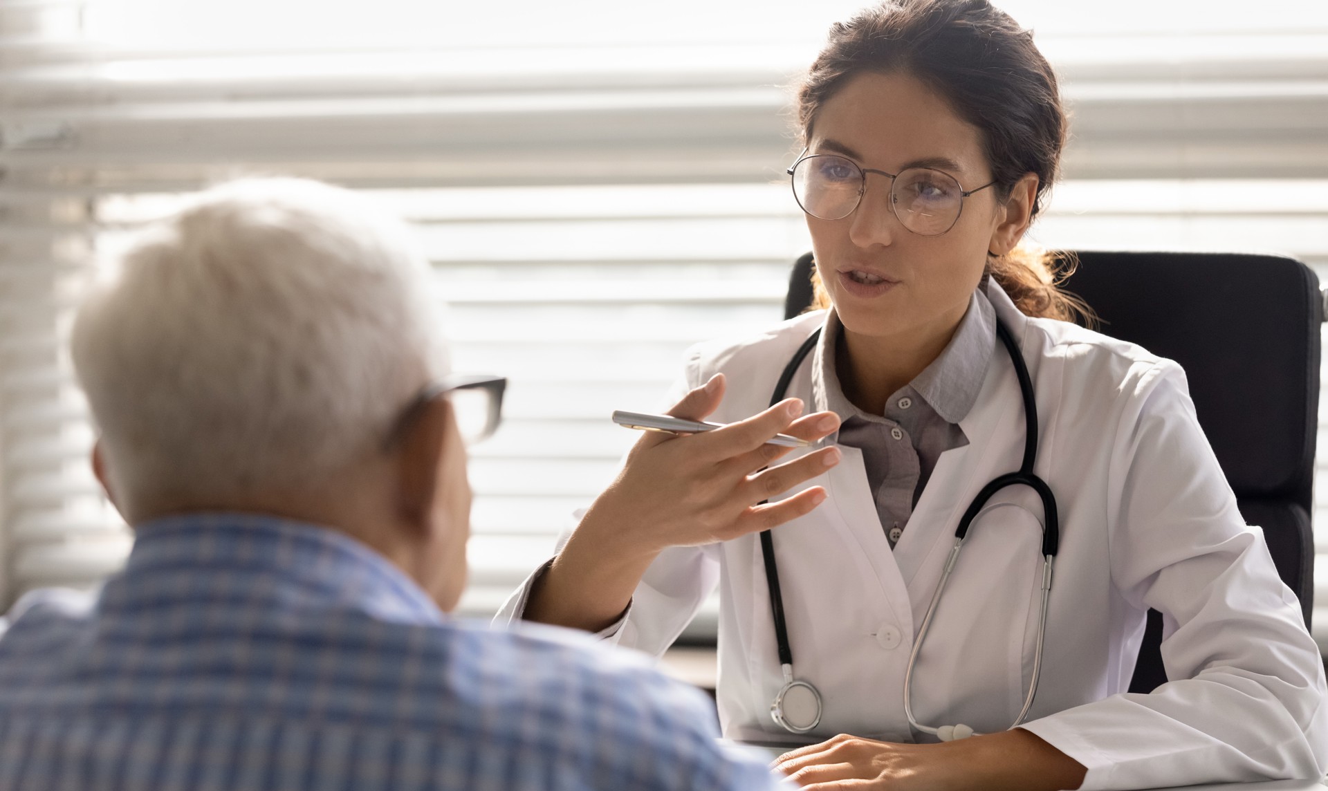 Lege bak pult og eldre pasient sitter foran. Illustrasjonsfoto: Colourbox