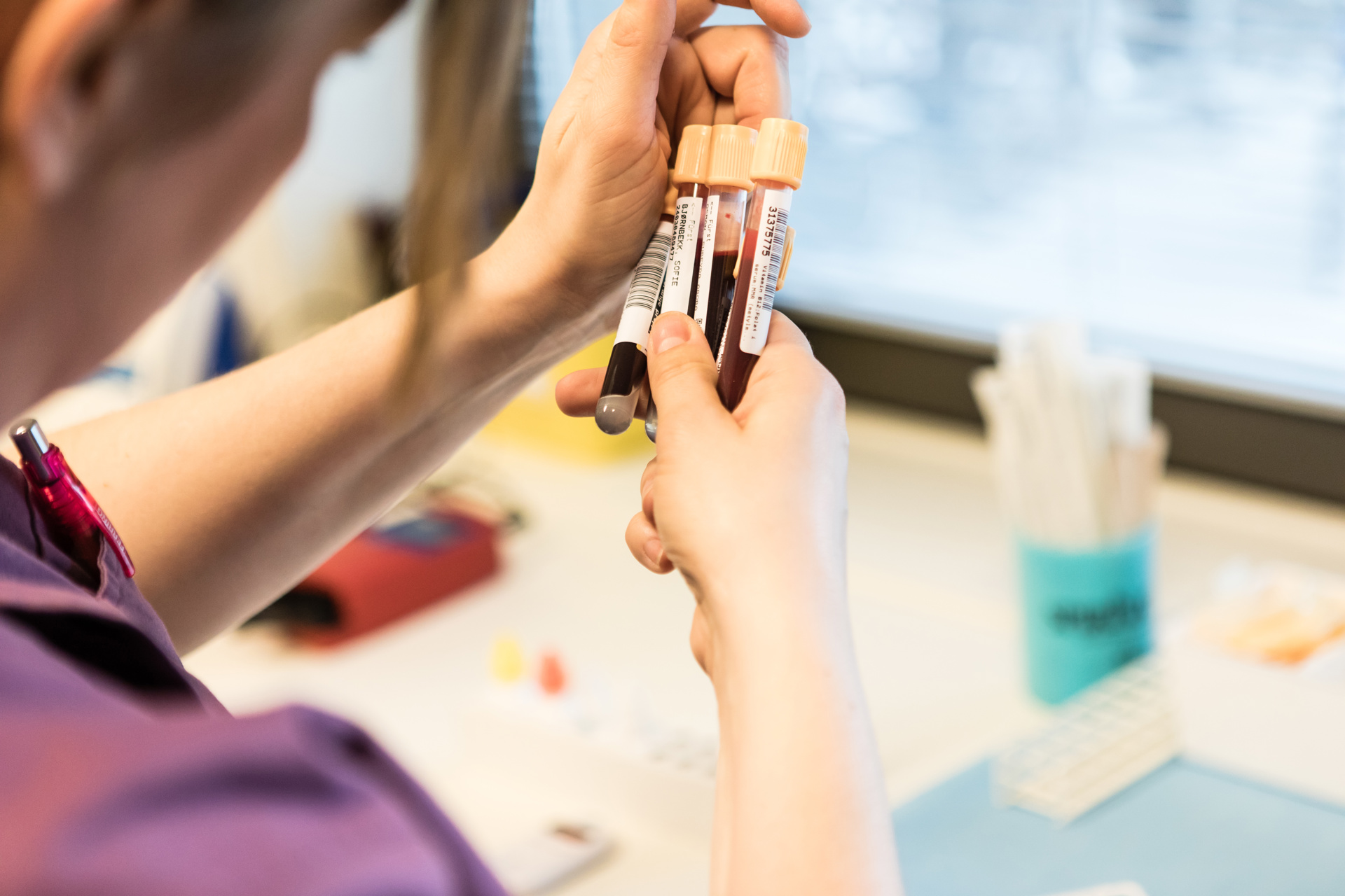 Legesekretær holder fire blodprøverglass